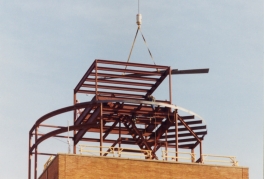 A photograph of the assembly of the helipad with a crane lifting structural beams into place