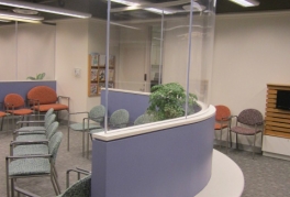 A view of a curved glass partition wall with incorporated bench seating in the waiting area
